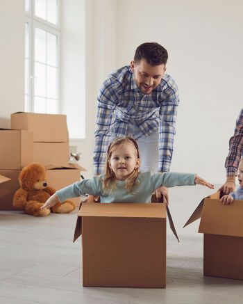 Family surrounded by moving boxes, children playing inside them